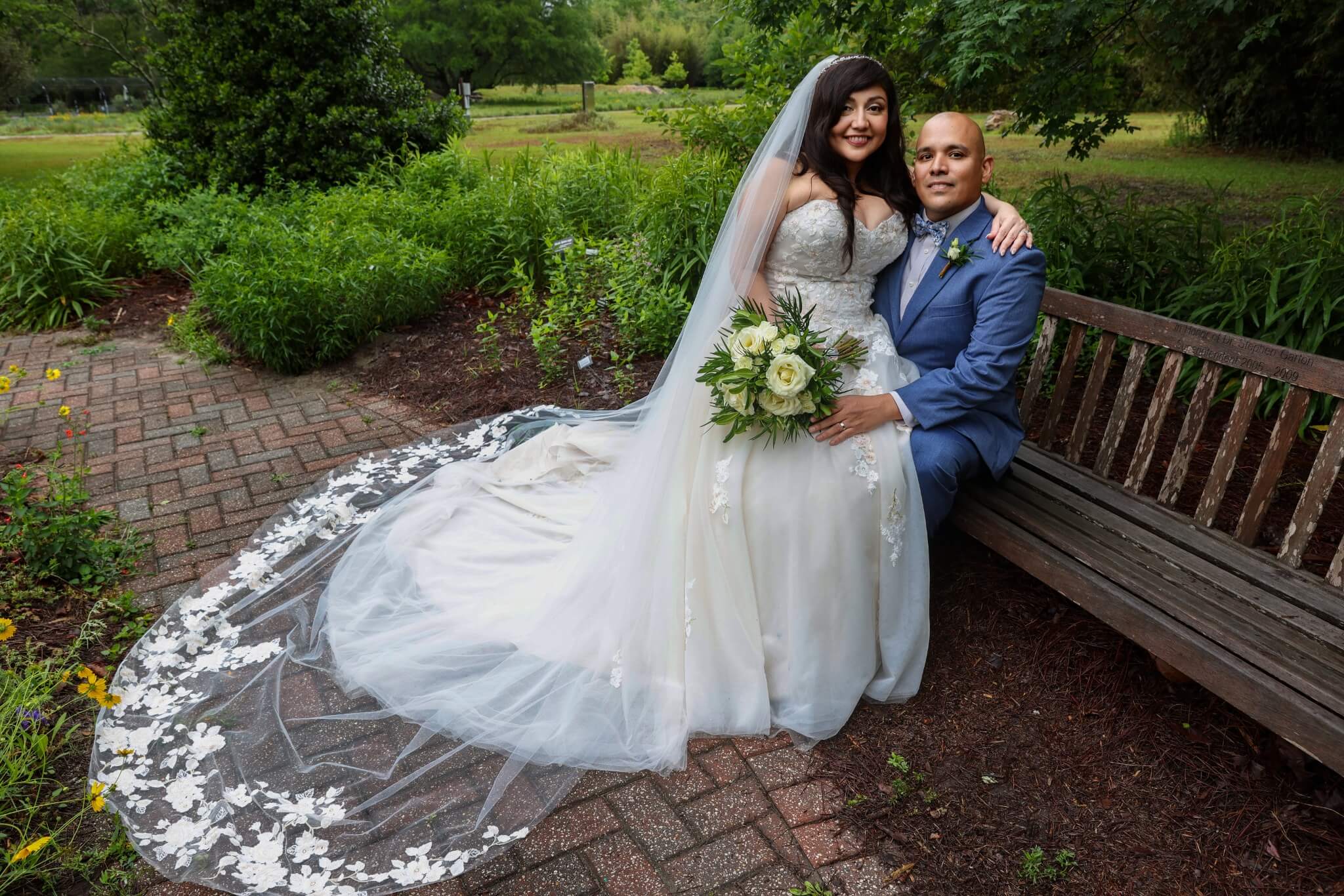 A bride and groom in a moss-draped Savannah garden, the bride's veil cascading across red brick